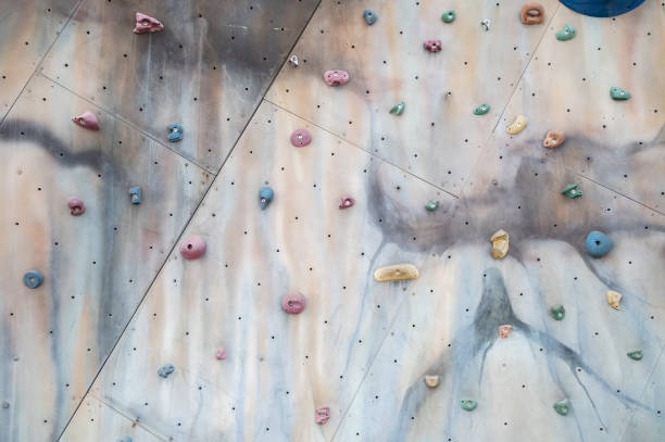 Street artificial rock climbing wall close-up view various colored grips. Colorful footholds for training. Orange climbing wall background