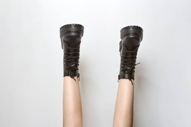 istock Woman legs in black combat boots on high heel platform with lug soles upside down, white background 1472711240