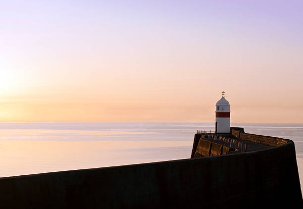 istock Lighthouse at the end of a breakwater wall during sunrise 147271252