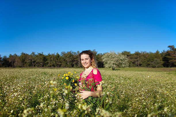 Beautiful young woman standing in blooming meadow stock photo