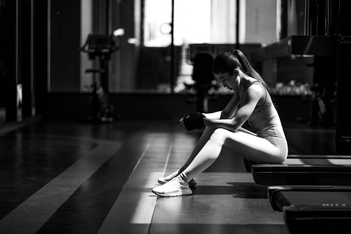 black and white Fitness young woman sitting in the gym and resting after doing a workout.