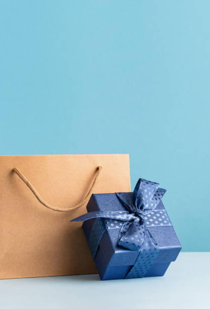 istock one gift box with a blue bow and paper bag on desk 1472722930