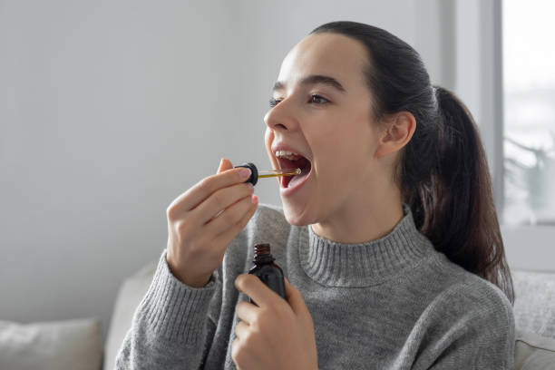 woman using cbd oil - druppelfles stockfoto's en -beelden