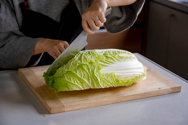 istock Woman cutting Chinese cabbage on cutting board. 1472727038