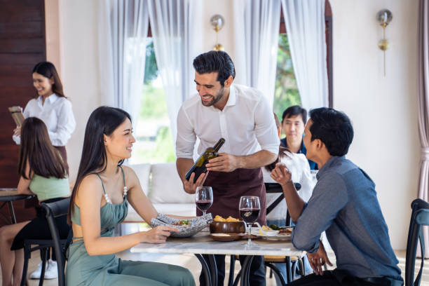istock Caucasian waiter receiving order serving from customer in restaurant. Attractive server service man working, taking note, writing order from consumer with pen at table in dining room with happiness. 1472728139