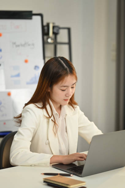 istock Young female accountant checking online information on laptop computer at her desk. 1472729367