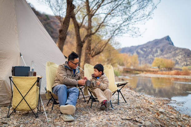 le temps de camping d’automne tranquille du père et du fils au bord de la rivière - camping family tent couple photos et images de collection