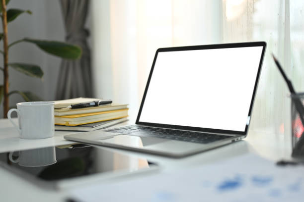 istock Laptop computer with white empty screen, cup of coffee and digital tablet on white working desk. 1472730049