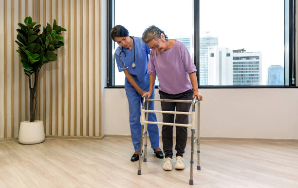istock Woman physical therapist in blue uniform help an elderly to exercise and practice walking on walker or cane. Healthcare and medicine concept. 1472734777