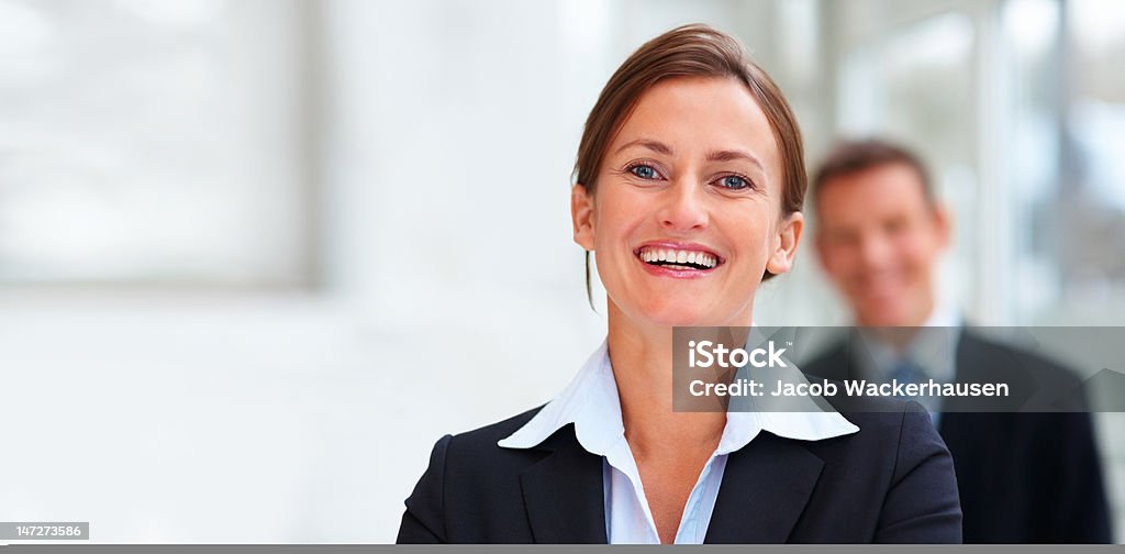 Femme d'affaires souriant avec des collègues en arrière-plan - Photo de Affaires d'entreprise libre de droits