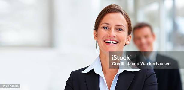 Donna Daffari Sorridente Con I Colleghi In Background - Fotografie stock e altre immagini di Organizzazioni aziendali