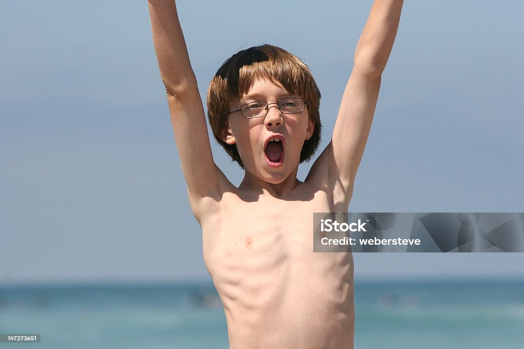 Victory Boy at beach with his arms up screaming Slim Stock Photo