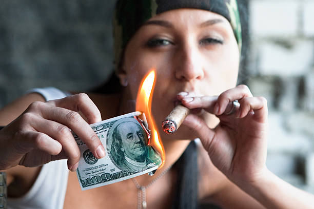 Pretty smoker Pretty girl is lighting a cigar from one hundred dollars bill. smoking women luxury cigar stock pictures, royalty-free photos & images