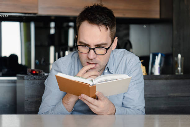 istock leisure, literature and people concept reading book at home. reader is reading interesting novel. student is studying textbook. guy is holding a book in his hand. guy is passionate about reading 1472738054