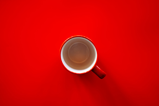 Flat lay of empty red coffee cup on red background