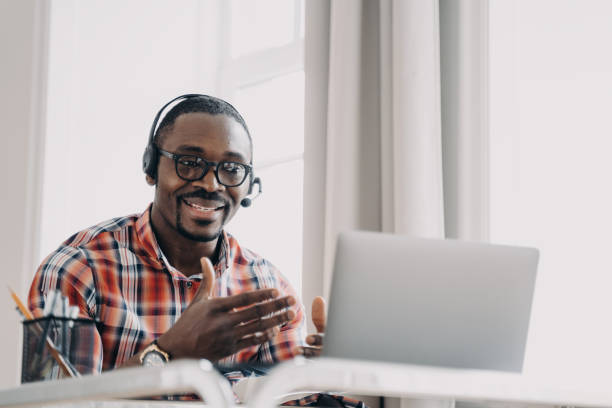 istock African american man wearing headset communicates with client by video call at laptop. Remote work 1472741043