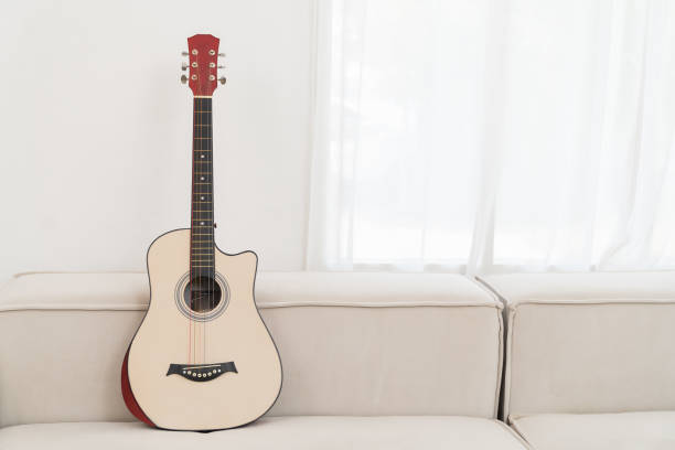 istock Acoustic guitar on white sofa at home. Background, copy space and interior design concept 1472744637