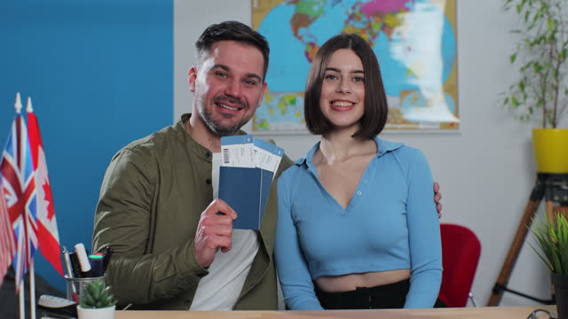 Portrait of a happy young couple in a travel agency, they are getting plane tickets for a summer trip. Travelling concept.