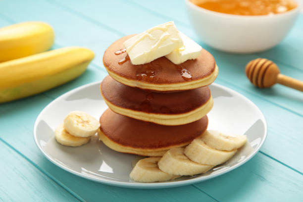istock Plate with yummy banana pancakes on blue background. 1472746268