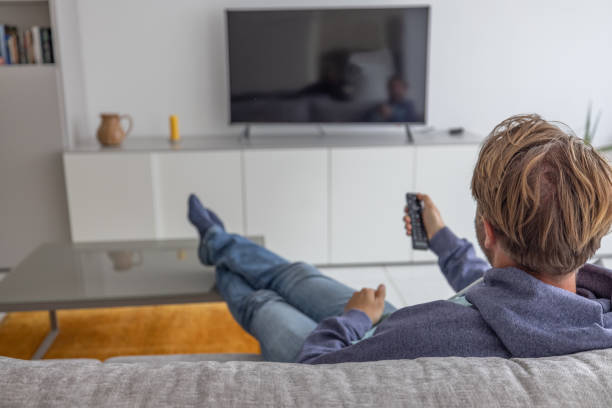 istock Man watching tv at home 1472747460