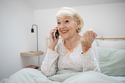 Older woman is sitting in bed and talking to her physician about her medicine