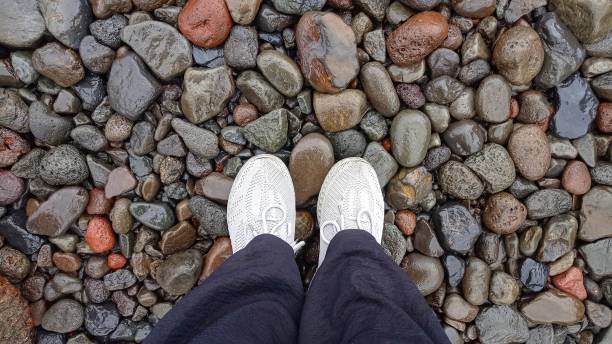 istock Low Section of Person Standing on Wet Pebbles 1472751239