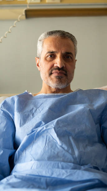 istock Senior sick man looking at camera while lying in hospital 1472755447