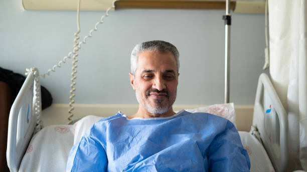 istock Senior man smiling while lying in hospital room 1472755475