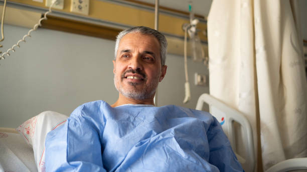 istock Senior man smiling while lying in hospital room 1472755526