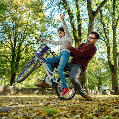 Father teaching his daughter to cycle in the park