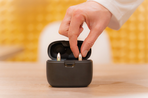 Hand of an audiologist doctor placing a hearing aid in its case.
