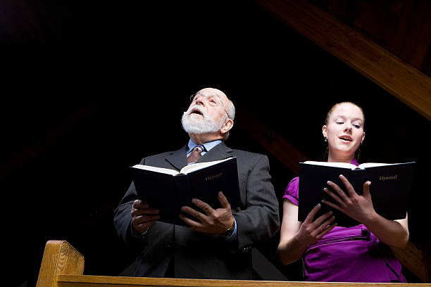 Senior White Man Young Woman Singing in Church Holding Hymnals stock photo