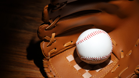 Baseball bat, leather glove and ball on green grass against dark background, closeup. Space for text