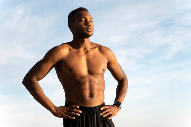 African american muscular guy in black beach shorts sunbathing at bright beach Young african american muscular guy in black beach shorts sunbathing at bright beach. Beautiful summer weather. Stock photo hot handsome man stock pictures, royalty-free photos & images