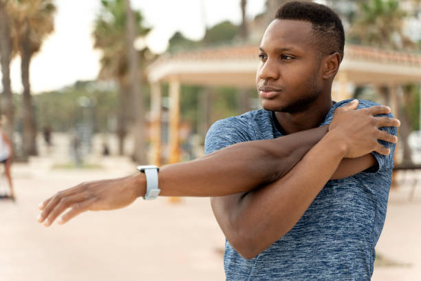 istock Concentrated man is stretching hands morning by sea beach 1472767795