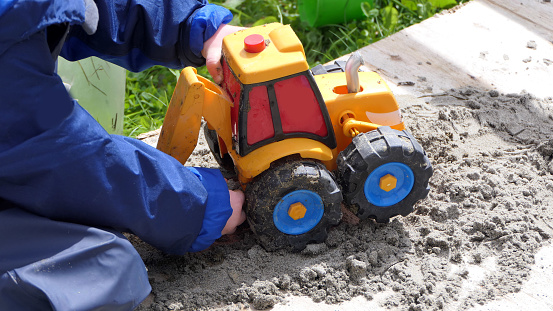 Red headed Child playing with toys in a Sand Pit