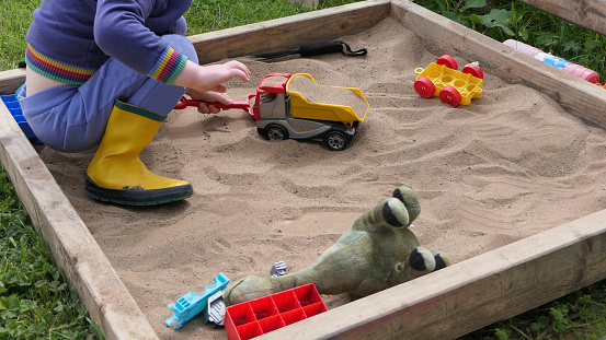 A Child playing with toys in a Sand Pit