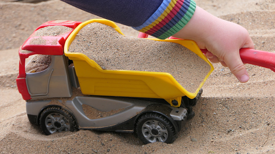 A Child playing with toys in a Sand Pit