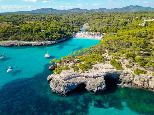 Aerial view of floating boats in Cala Llombards (Santanyi) beach bay in Mallorca Island in Spain during summer sunny day