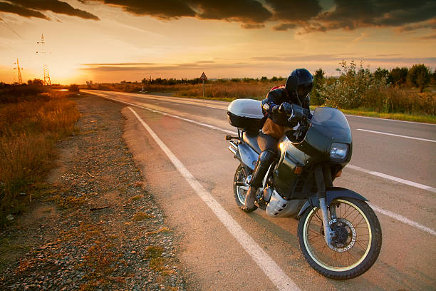 istock Biker and motorcycle on road at sunset 147277057