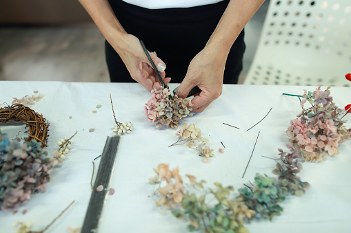 A female floral teacher is making a wreath using preserved hydrangeas