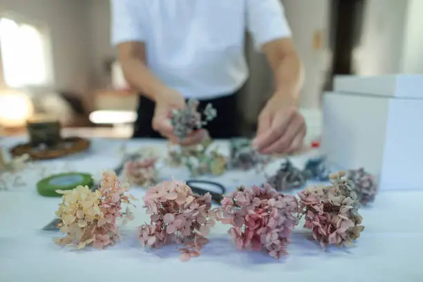 A female floral teacher is making a wreath using preserved hydrangeas