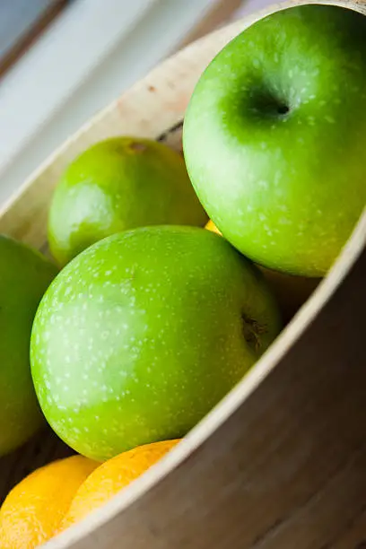 A wooden bowl of fresh ripe green apples