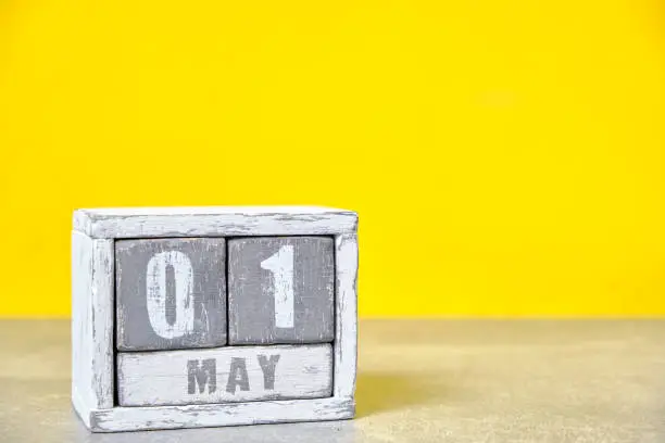 May 1, Wooden desktop calendar yellow background.Spring month depicted on cubes.Place for your ideas.Labor day