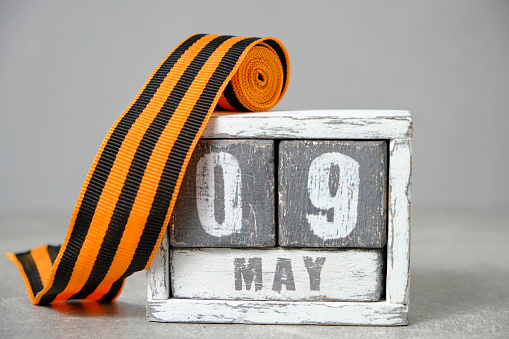 May 09, wooden calendar and St. George ribbon gray background.Concept for Victory Day over fascism