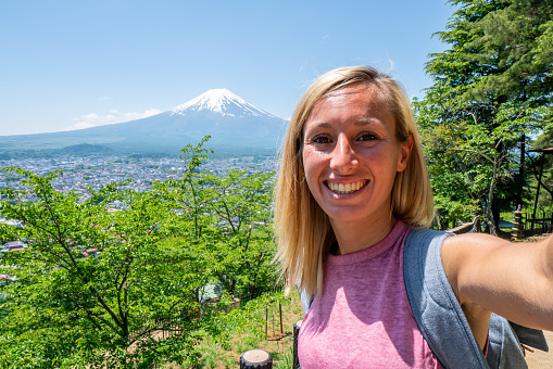 She love it, flowers blooming.
Woman travels in Japan and takes a selfie with beautiful landscape and the Mt Fuji