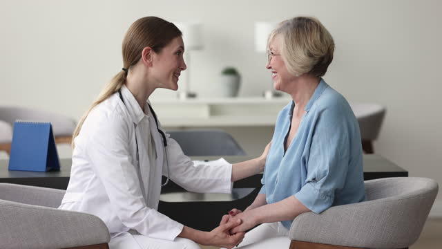 Happy positive doctor woman giving support to senior patient