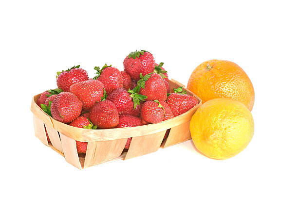 Ripe red strawberries in a basket alongside lemon and orange