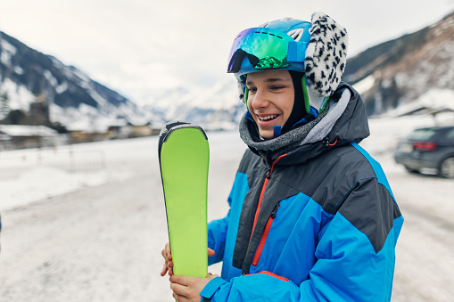 Portrait of a happy teenage boy holding skis that is going to ski in the Austrian Alps. The boy is wearing ski helmet.
Canon R5