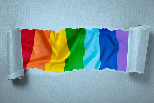 Background of torn cardboard showing Rainbow Flag